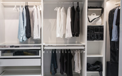 Young European man with dark hair brings wardrobe order puts everything in its place hides things in boxes. Closet organized. Capsule wardrobe.